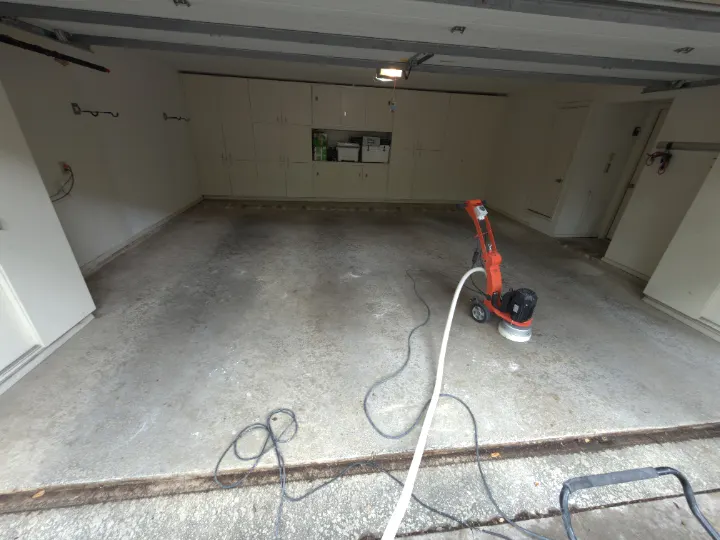 Dallas garage floor during removal of a failing textured paint coating before epoxy installation.