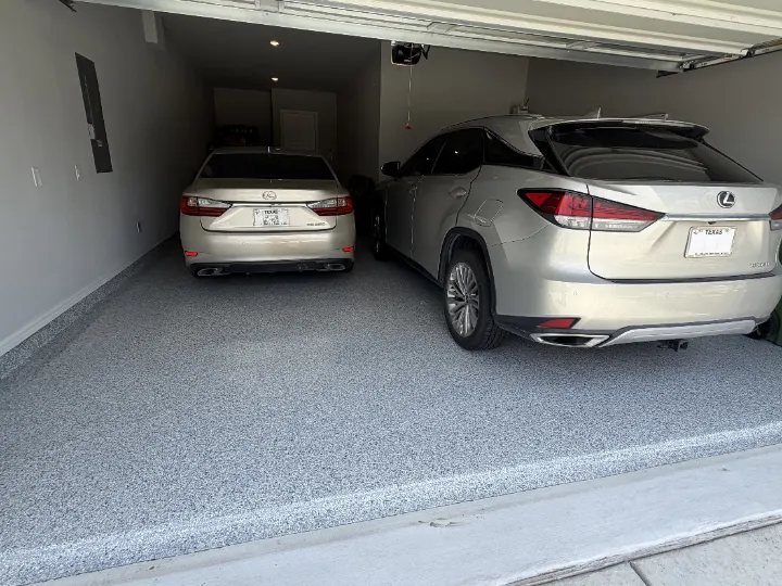 Garage with epoxy floor coating in Light Grey with Tidal Wave flake blend, with two cars parked.